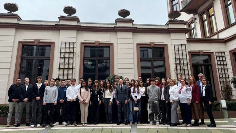 Mehrere Menschen stehen vor Gebäude.