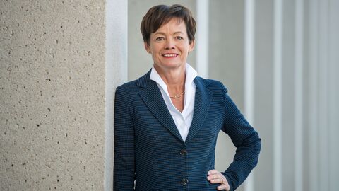 Lucia Puttrich lehnt an einer Säule in einer Säulenhalle und lächelt in die Kamera