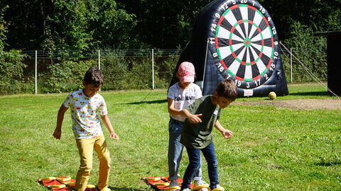Kinder spielen auf einer Wiese im Sonnenschein beim Drillingstreffen 2021