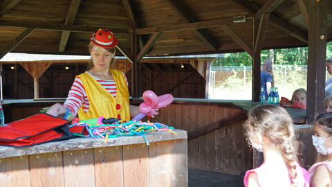 Eine als Clown verkleidete Frau baut Luftballon-Figuren für Kinder während des Drillingstreffen 2021