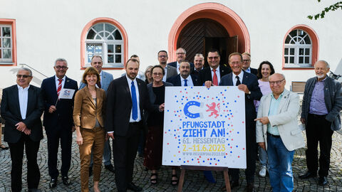 Das Logo des Hessentag 2023 in Pfungstadt wird von mehreren Personen präsentiert.