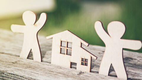 Zwei Holzmännchen neben einem kleinen Holzhaus