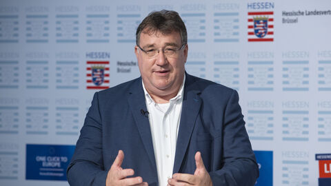 Europastaatssekretär Mark Weinmeister im dunklen Blazer mit weißem Hemd stehend an einem Pult während der Veranstaltung