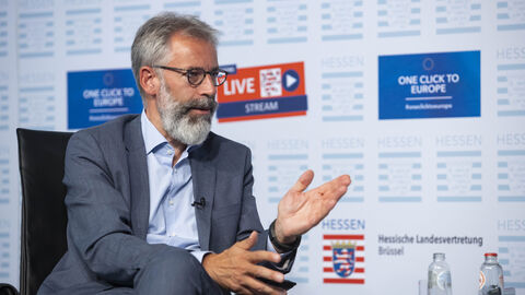 Michael Hager sitzend auf einem Podium im Gespräch mit anderen Gästen der Veranstaltung