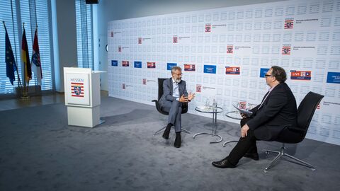 Michael Hager und Andreas Heitker auf Stühlen sitzend einander zugewandt im Gespräch während der Veranstaltung