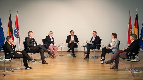 Europaabgeordnete der im Bundestag vertretenen Fraktionen diskutieren sitzend auf Stühlen auf dem Podium
