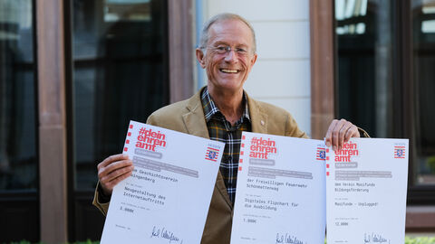Staatsminister Axel Wintermeyer hält drei Förderzusagen in der Hand