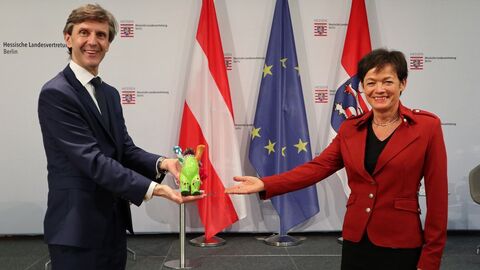 Botschafter Peter Huber und Staatsministerin Lucia Puttrich halten einen kleinen bemalten Berlin-Bären lächelnd in die Kamera