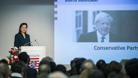 Die Rednerin steht auf der Bühne und erläutert eine Präsentation: Die britische EU-Korrespondentin Jennifer Rankin, The Guardian, hat das Wahlergebnis der britischen Parlamentswahl in der Hessischen Landesvertretung in Brüssel eingeordnet.