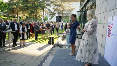 Im Freien, im Sonnenschein, eröffnet Staatsministerin Lucia Puttrich die traditionelle Schlenderweinprobe 2022 in der Hessischen Landesvertretung in Berlin