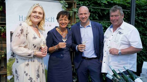Schauen lächelnd in die Kamera: Weinkönigin Annika, Europaministerin Lucia Puttrich, Ingmar Jung MdB (v.l.nr.) zu Gast am Stand von Hans Bausch (r.)