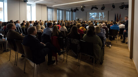 Viele Menschen sind von hinten zusehen, während auf Stühlen in mehreren Reihen sitzen und auf eine Leinwand schauen: Filmvorführung ZDF Fernsehfilm „Das schweigende Klassenzimmer“