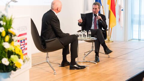 Zwei Männer in dunklen Anzügen sitzen sich auf einer Bühne gegenüber: Andreas Meyer-Feist, Leiter des HR-Hörfunkstudios in Brüssel im Gespräch mit Kommissar Günther H. Oettinger