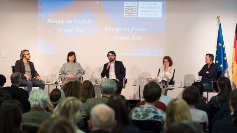 Drei Männer und zwei Frauen sitzen auf einer Bühne. Im Hintergrund sieht man eine Präsentation und im Vordergrund ist ein Teil des Publikums zu sehen: v.l.n.r.: Massimo Gezzi (IT), Justyna Bargielska (PL), Federico Italiano (IT), Nora Bossong (DE), Frédéric Forte (FR)