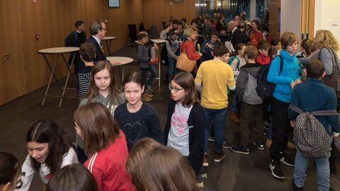 Vorlesewettbewerb 2019 Viele Kinder, die um Tische stehen und sich unterhalten.