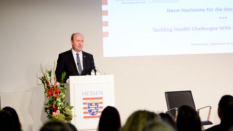 Uwe Becker, Hessischer Staatssekretär für Europaangelegenheiten, steht am Rednerpult und spricht zu den Teilnehmern im Saal