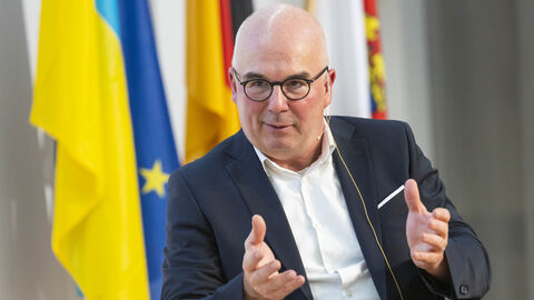 Dr. Detlef Fechtner, Chefredakteur der Börsenzeitung hat die Veranstaltung moderiert -hier in Nahaufnahme im Gespräch mit gestikulierenden Händen auf der Bühne fotografiert