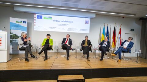 Die Teilnehmer Podiumsdiskussion sitzen auf der Bühne und sprechen miteinander