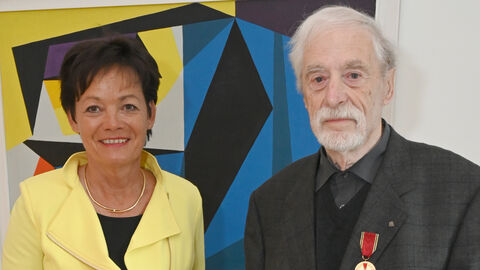 Europaministerin Puttrich neben Wilfried Schweitzer, beide halten gemeinsam die Urkunde in Händen und lächeln in die Kamera.