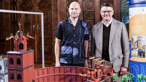 Ministerpräsident Boris Rhein und PLAYMOBIL-Künstler Oliver Schaffer stehen vor dem Diorama der Paulskirche.