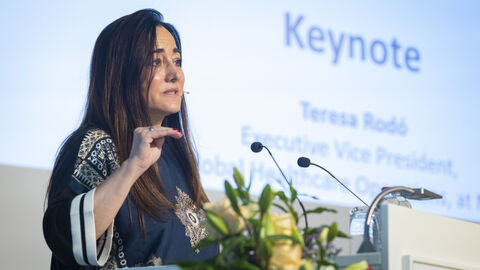 Frau steht am Rednerpult und spricht zum Publikum