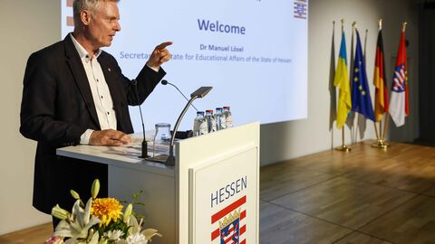 Dr. Manuel Lösel Ein Mann spricht am Rednerpult zum Publikum
