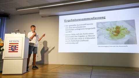 Erläuterung der Projekte Ein junger Mann steht auf der Bühne, erläutert ein Projekt