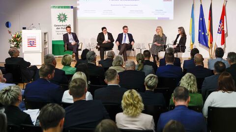 Fünf Personen sitzen auf Stühlen im Halbkreis auf der Bühne, unterhalten sich im Rahmen der Podiumsdisskussion