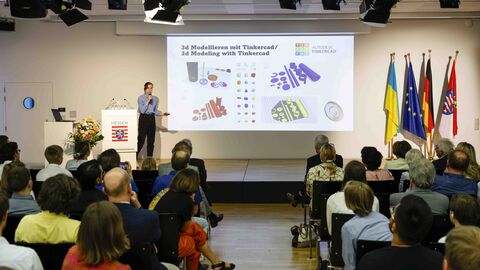 Eine Frau steht auf der Bühne und erläutert ein 3D-Projekt