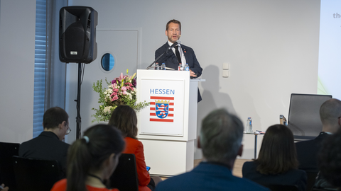 Sprecher steht am Rednerpult auf der Bühne und spricht