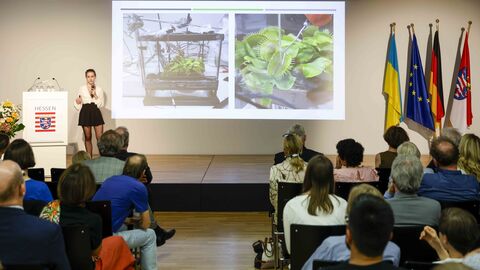 Eine Frau steht auf der Bühne, erläutert ein Projekt zu Venusfliegenfallen