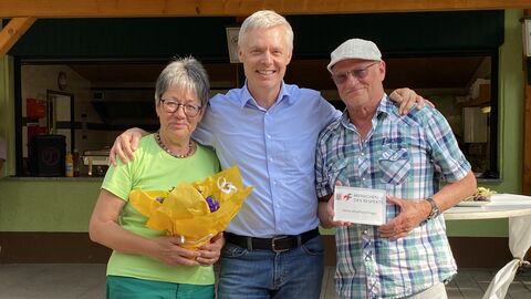Dr. Manuel Lösel (Mitte), Staatssekretär im Hessischen Kultusministerium, der „Mensch des Respekts“ Henry Manfred Klinger (rechts), der seine Auszeichnung in seinen Händen hält, und eine Frau (links) vor einem Gebäude