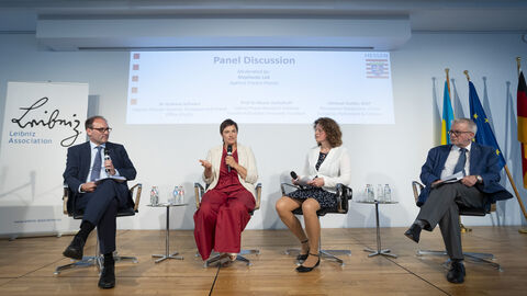 Vier Personen sprechen während der Podiumsdiskussion auf der Bühne miteinander