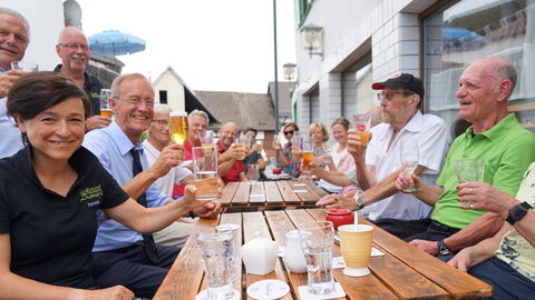 Der Chef der Hessischen Staatskanzlei, Staatsminister Axel Wintermeyer, mit Bürgerinnen und Bürgern an einem Tisch auf einer Terrasse vor der „VolksWirtschaft Lindenhof“