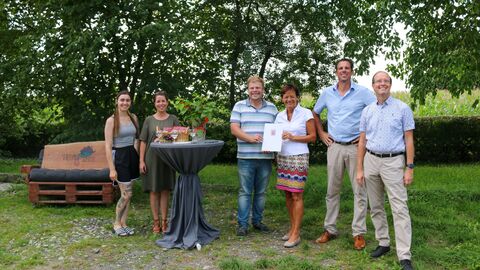Lucia Puttrich auf einer grünen Wiese vor Bäumen gemeinsam mit Mitgliedern des Wein- und Kulturvereins.