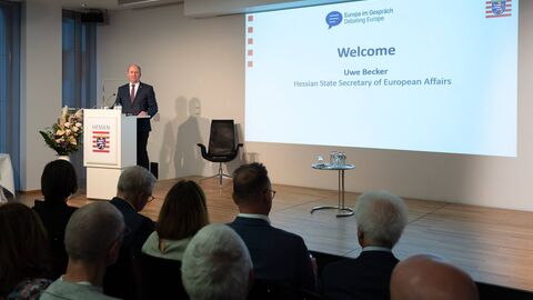 Uwe Becker steht auf der Bühne und eröffnet die Veranstaltung