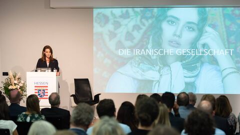 Frau Amiri steht am Podium und spricht zum Publikum