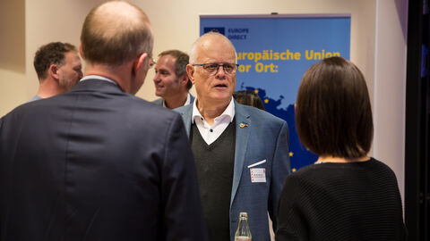 Austausch der Mitglieder des Europanetzwerks Es sind mehrere Menschen von hinten und von vorne abgebildet, die im Gespräch sind.