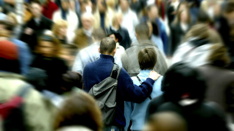 Menschenmenge im öffentlichen Raum, mit Fokus auf zwei Menschen, die von hinten zu sehen sind