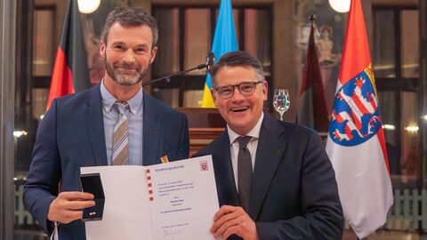 Ministerpräsident Boris Rhein mit Stephan Sorg vor Flaggen.  