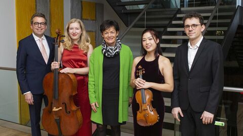 Gruppenfoto mit fünf lächelnden Personen in Abendgarderobe (v.l.n.r.): Prof. Dr. Friedemann Eichhorn, Cellistin Anouchka Hack, Staatsministerin Lucia Puttrich, Violinistin Claire Wells und Pianist Itai Navon