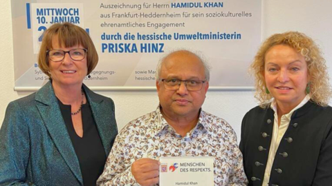 Für sein ehrenamtliches Engagement hat Staatsministerin Priska Hinz (links) Hamidul Khan (Mitte) als „Menschen des Respekts“ ausgezeichnet. Staatsministerin Priska Hinz (links), Hamidul Khan (Mitte) mit seiner „Menschen des Respekts“-Auszeichnung in seinen Händen sowie eine weitere Frau (rechts)