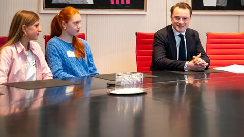 Zwei Schülerinnen sitzen neben Benedikt Kuhn, Chef der Staatskanzlei