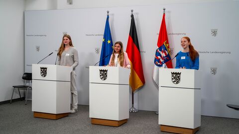 Drei Schülerinnen stehen jeweils an einem Rednerpult.