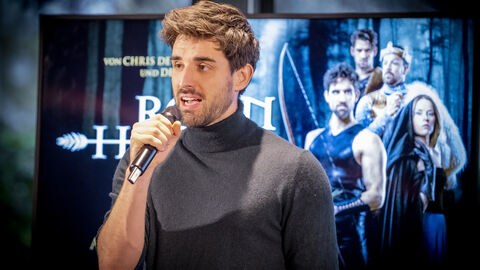 Mann mit Mikrophon auf der Bühne: Philipp Büttner (spielt Robin von Loxley) singt „Freiheit für Nottingham“