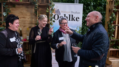 Schlenderweinprobe 2024 Europaminister Pentz (rechts) steht neben drei Frauen. Alle haben Weingläser in der Hand und befinden sich im Gespräch.