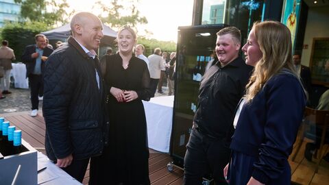 Eine neue Generation Winzer: Zum ersten Mal präsentierten die Jungwinzer Julia Schönberger (r.) und Max Katz (2.v.r.) ihre Weine in der Landesvertretung Menschen vor einem Kühlschrank mit Weinflaschen lächelnd gemeinsam im Gespräch: Zum ersten Mal präsentierten die Jungwinzer Julia Schönberger und Max Katz ihre Weine in der Landesvertretung