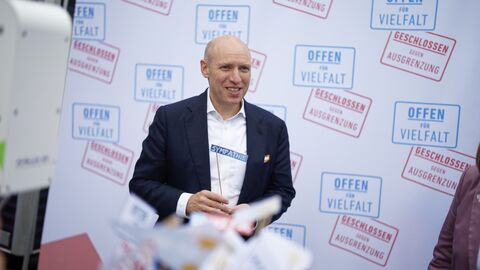 Staatsminister Manfred Pentz am Stand der sozialen Landwirtschaft Hephata, deren Mitarbeiter die Mitmachaktion „Offen für Vielfalt“ auf dem Hessenfest präsentierten. Staatsminister Manfred Pentz. Im Vordergrund kleine Flaggen.