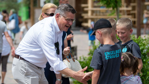 Ministerpräsident Rhein begrüßt die jungen Teilnehmer. Ministerpräsident Rhein mit drei schüttelt die Hand eines Jungen, nebendran weitere Kinder.