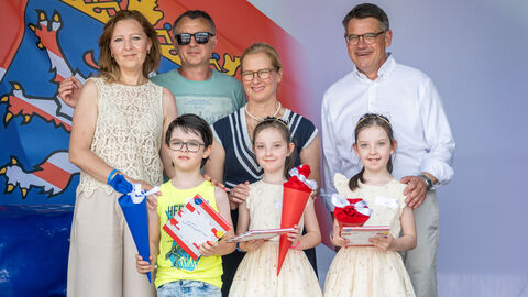 Ministerpräsident Rhein und seine Frau beim Treffen mit einer Drillingsfamilie. Ministerpräsident Rhein und seine Frau mit einer Drillingsfamilie